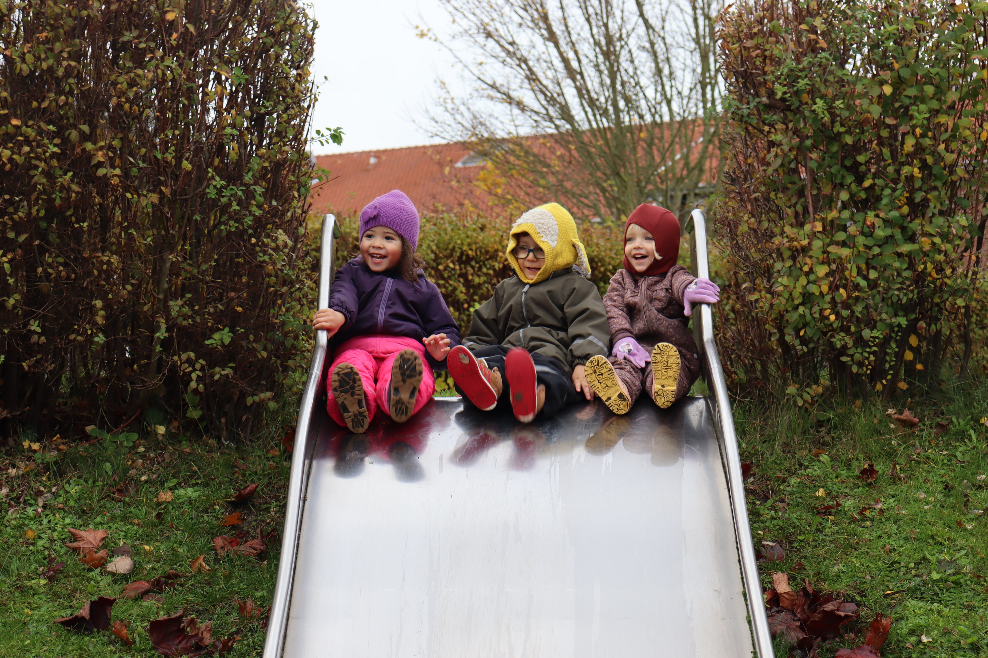 3 børn sidder på toppen af en stor rutsjebane